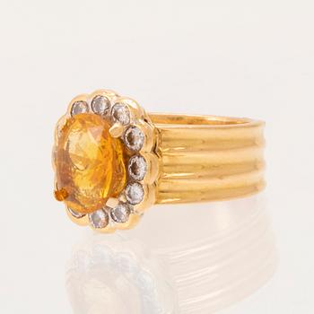 A 22K gold carmosé ring with an oval faceted yellow sapphire and round brilliant-cut diamonds.