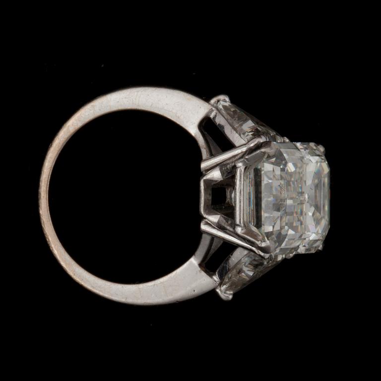 A baguette-cut diamond, 9.30 cts, ring. Quality I/VVS2. Flanked by two triangular diamonds approximately 1.00 ct each.