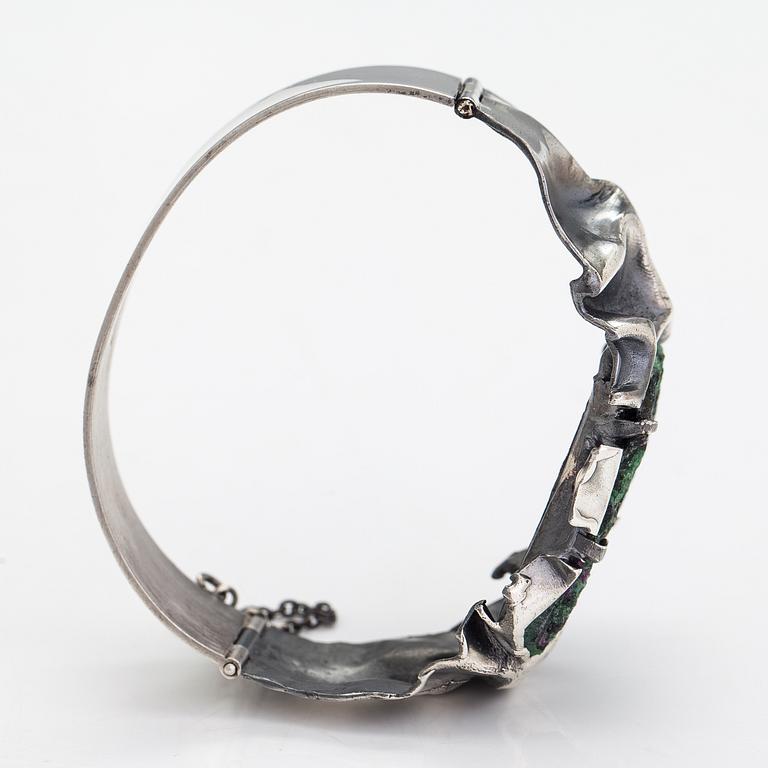 Reino Saastamoinen, Armband "Maahiset", siver och zoisit med rubinkristaller. Helsingfors 1968.