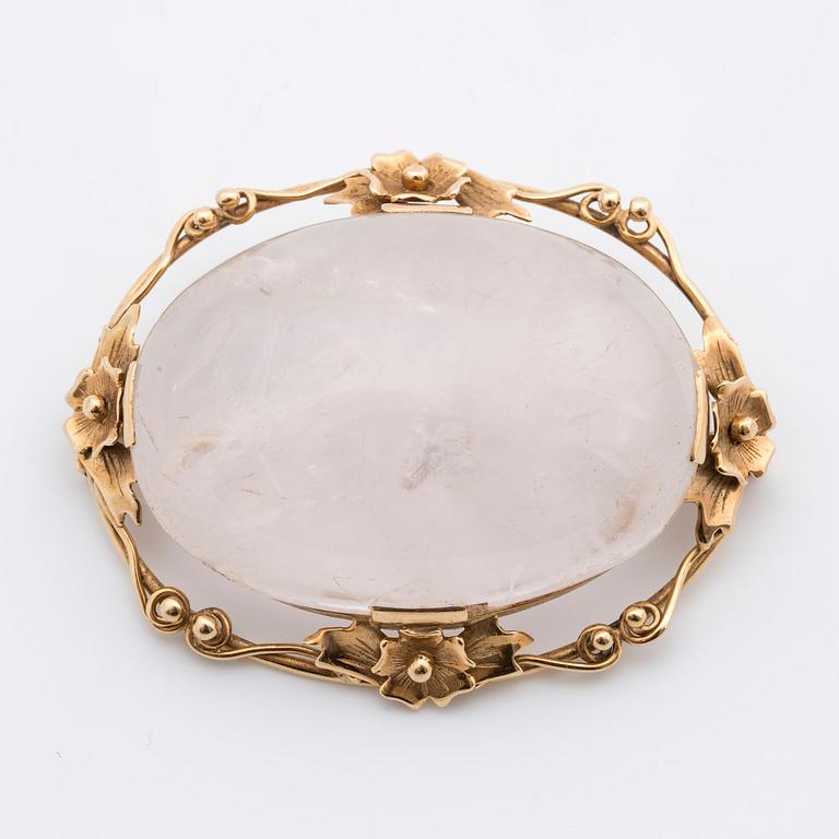 A cabochon-cut rose quartz brooch.
