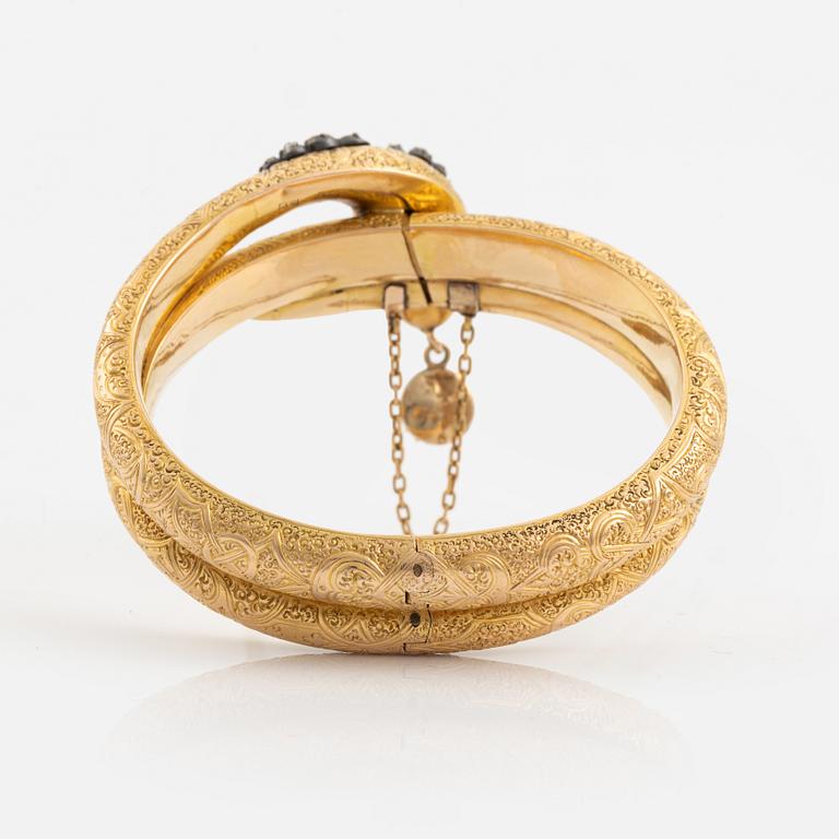 A Victorian snake bracelet in 14K gold with rose-cut diamonds, red stones and a half pearl.