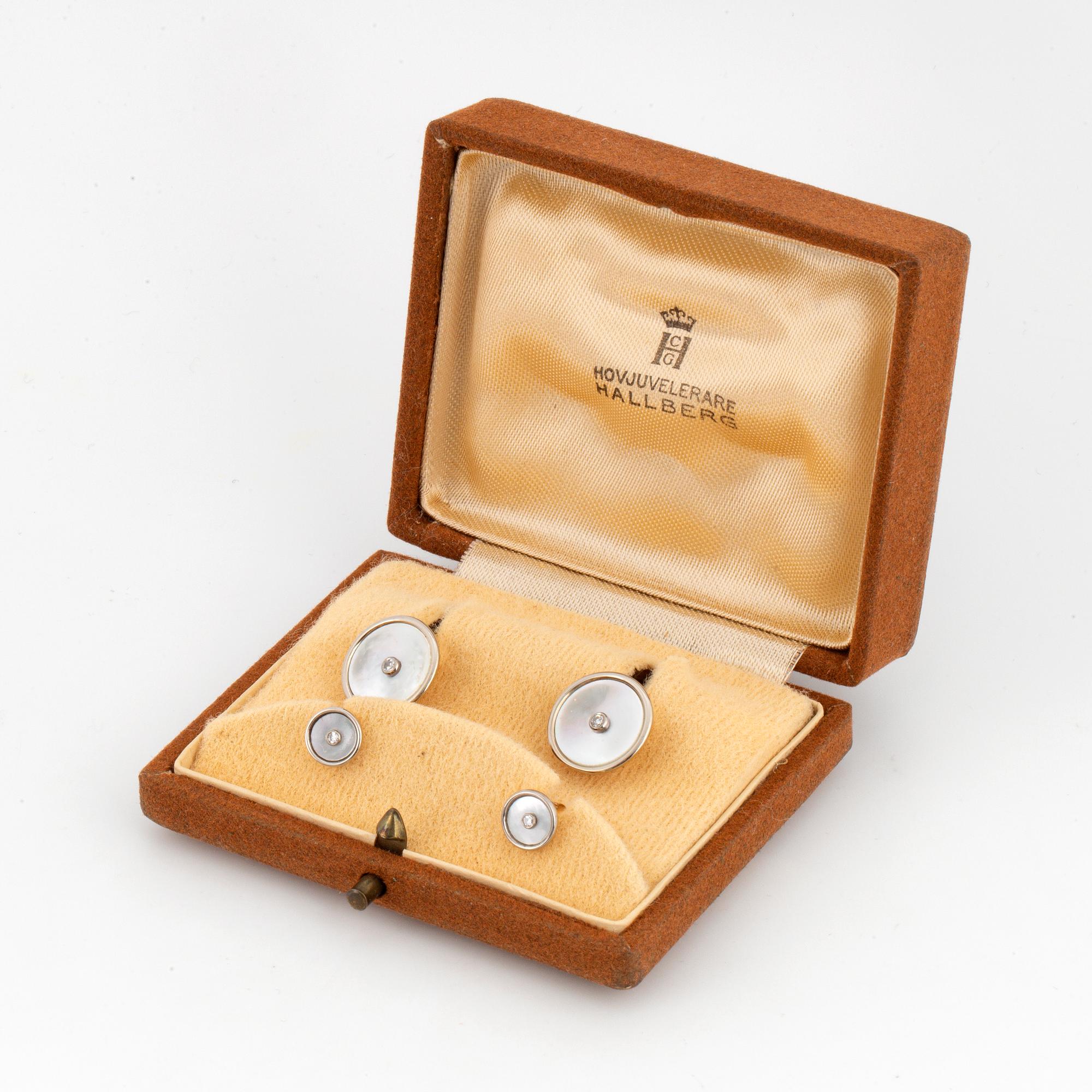 A pair of cufflinks and a pair of shirt buttons.
