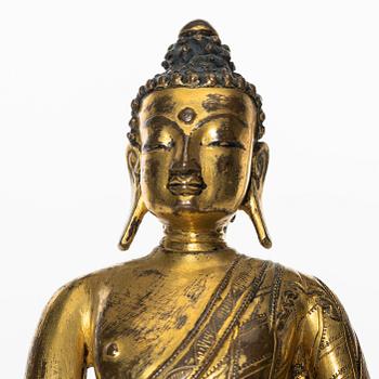 A gilt copper-alloy figure of Aksobhya Buddha, 14th/15th century, Tibet or Nepal.