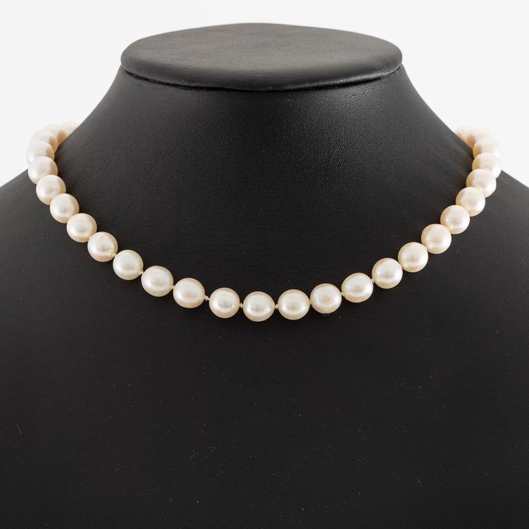 Pearl necklace, cultured pearls with a clasp in 18K white gold set with emeralds, diamonds, and pearls.