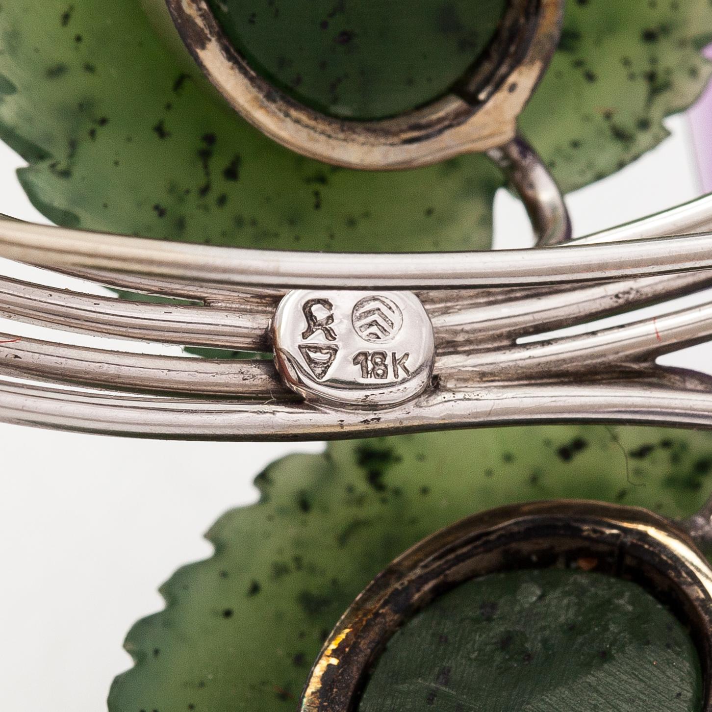 Rintaneula, 18K valkokultaa, veistettyjä ametisteja ja nefriitteja, timantteja n. 0.64 ct yht.