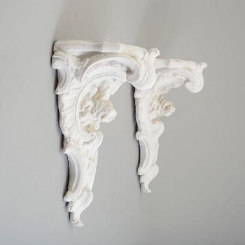 A pair of consoles and a set of three decor-elements, plaster, 20th century.