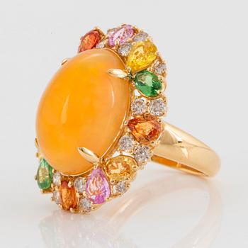 An 18K gold ring set with an opal, round brilliant-cut diamonds.