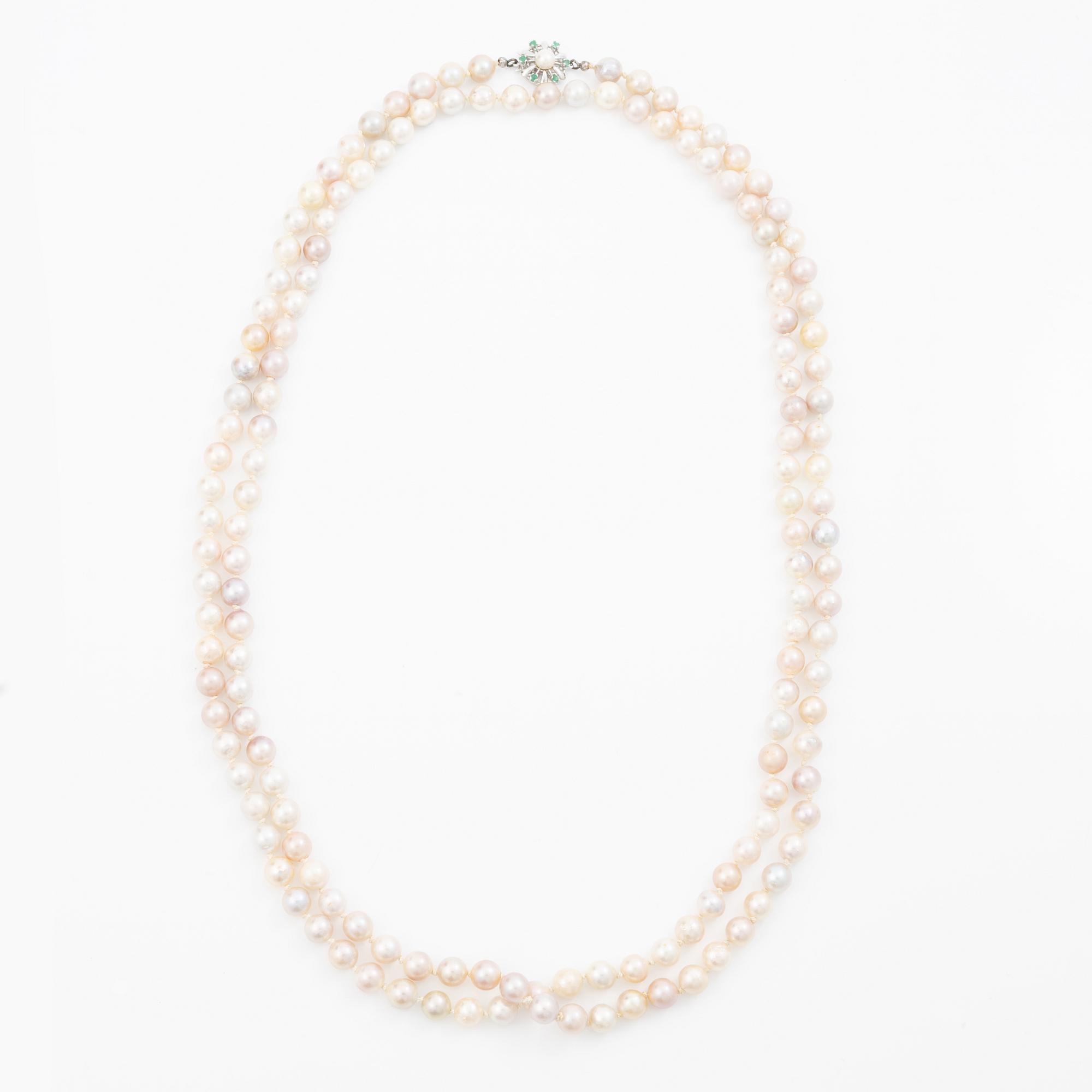 Long cultured pearl necklace with an 18K white gold clasp set with emeralds.