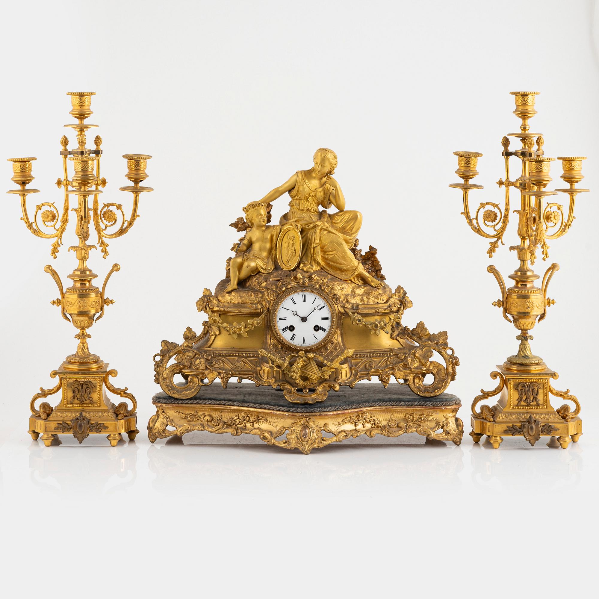 A table clock and a pair of candelabras, Louis XVI-style, France, beginning of the 20th century.