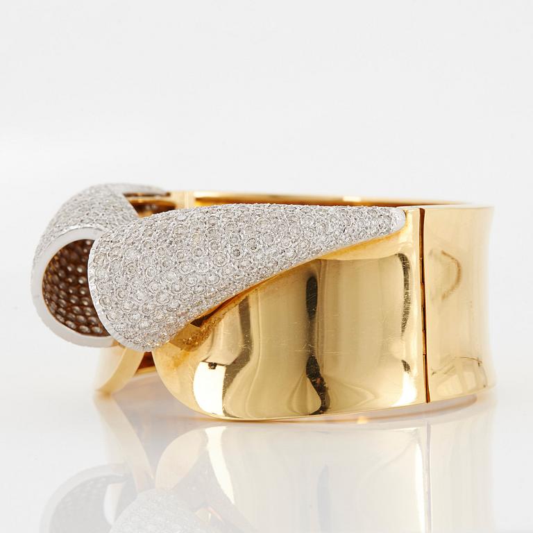 An 18K gold bangle set with round brilliant-cut diamonds.