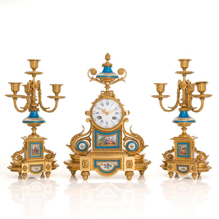 A mid-19th-century French gilt-brass mantel clock with a pair of candelabra by Dussault.