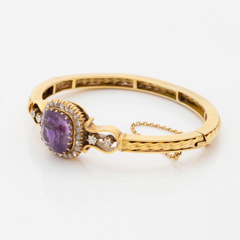 A 14K gold bangle set with a faceted amethyst and rose-and old-cut diamonds.