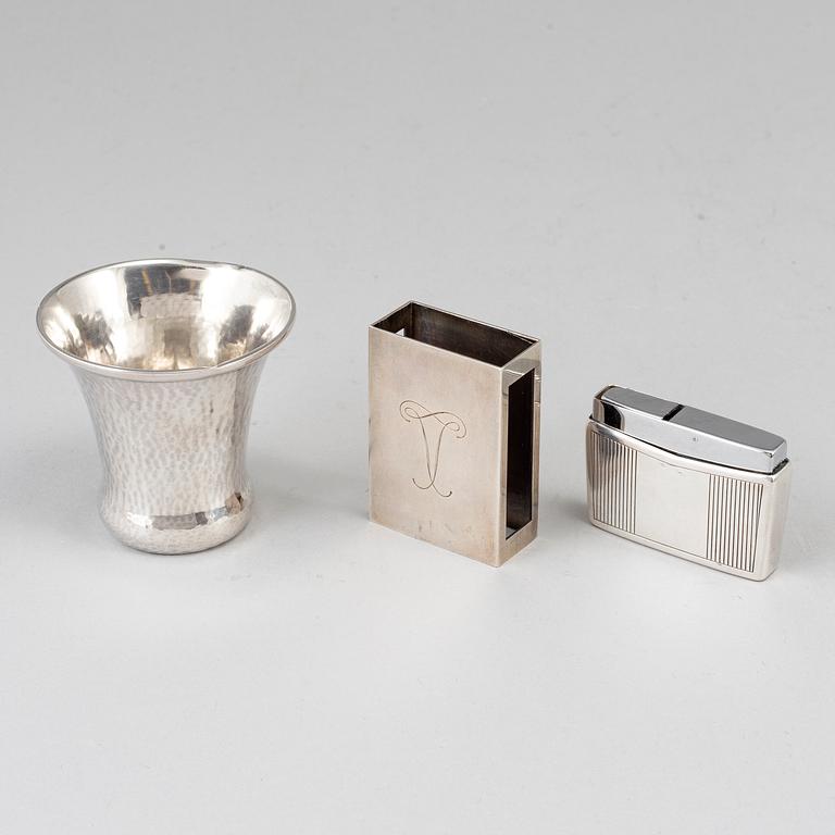 A silver vodkacup, lighter and matchholder.