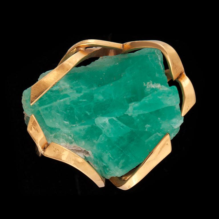 A gold ring set with an un-cut stone, probably emerald.