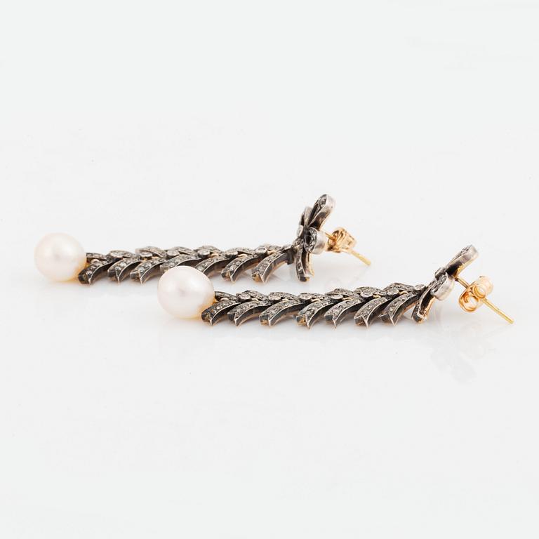 A pair of silver and 18K gold earrings with cultured pearls and set with eight-cut diamonds.