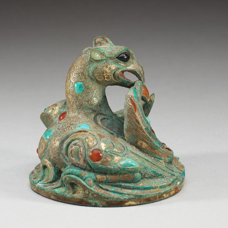 A gilt phoenix shaped bronze weight with inlay of stones.