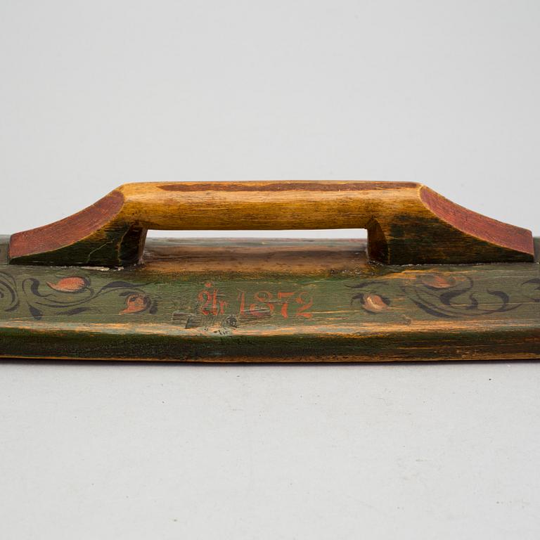 A painted folk art mangling board and sickel dated 1872 and 1847.