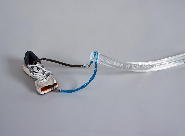 Yngve Holen, executed in 2014. Engraved acrylic glass, cable, lock, trainer, snap bracelet.