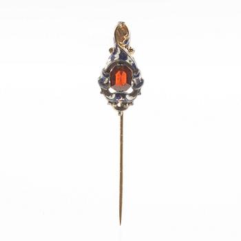 Tie pin of gilded brass with decoration of enamel and a faceted garnet, second half of the 19th century.