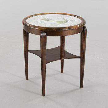 A table from the first halft of the 20th century with a "Kalmar Fajans" tabletop, painted by John Sjöstrand.