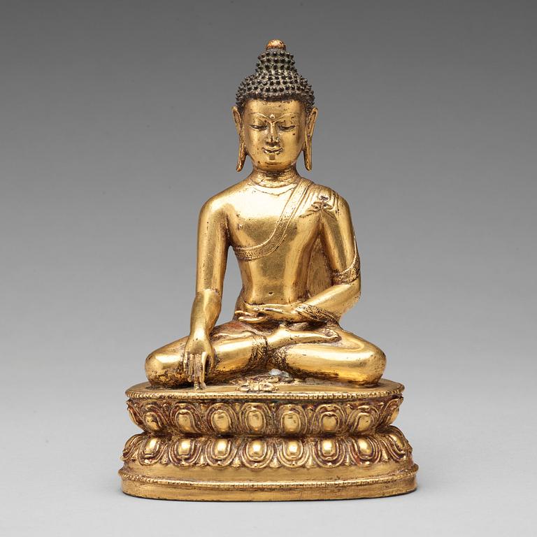 A gilt copper alloy figure of Akshobhya, Tibet, 16th Century.