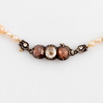 A pearl necklace with a silver and gold clasp set with rose-cut diamonds.