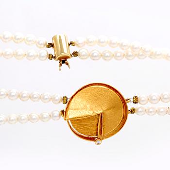 A necklace of cultured pearls and pendant in 18K gold with a brilliant cut diamond.