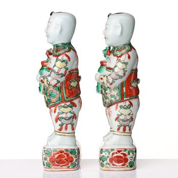 A pair of wucai decorated porcelain figurines of boys with flowers, Qing dynasty, Kangxi (1662-1722).