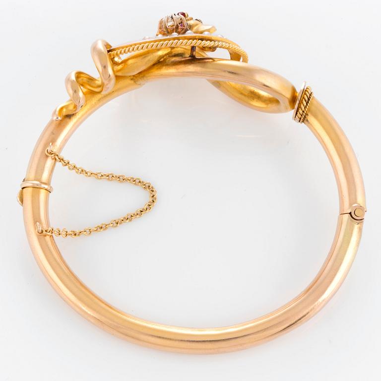 A snake bangle in 14K gold set with a rose-cut diamond, pearls and cabochon-cut rubies.