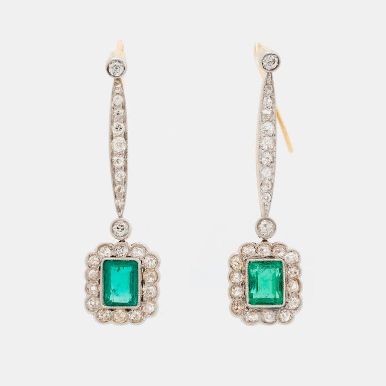 A pair of platinum and gold earrings set with step-cut emeralds and old-cut diamonds.