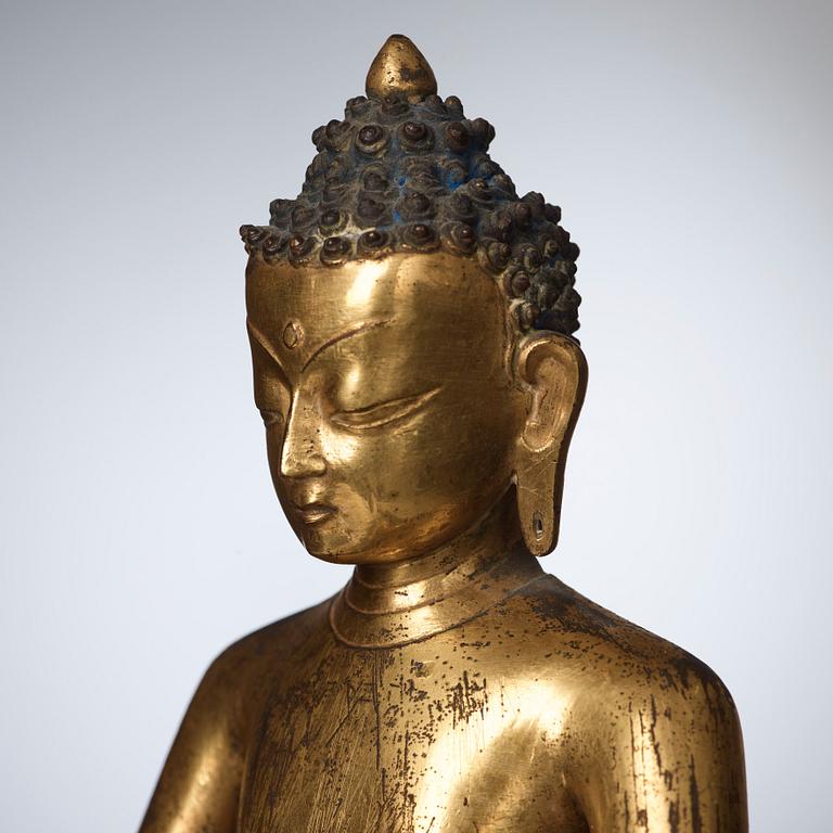 A large Nepalese gilt bronze buddha on a throne with mandorla, 18/19th Century.