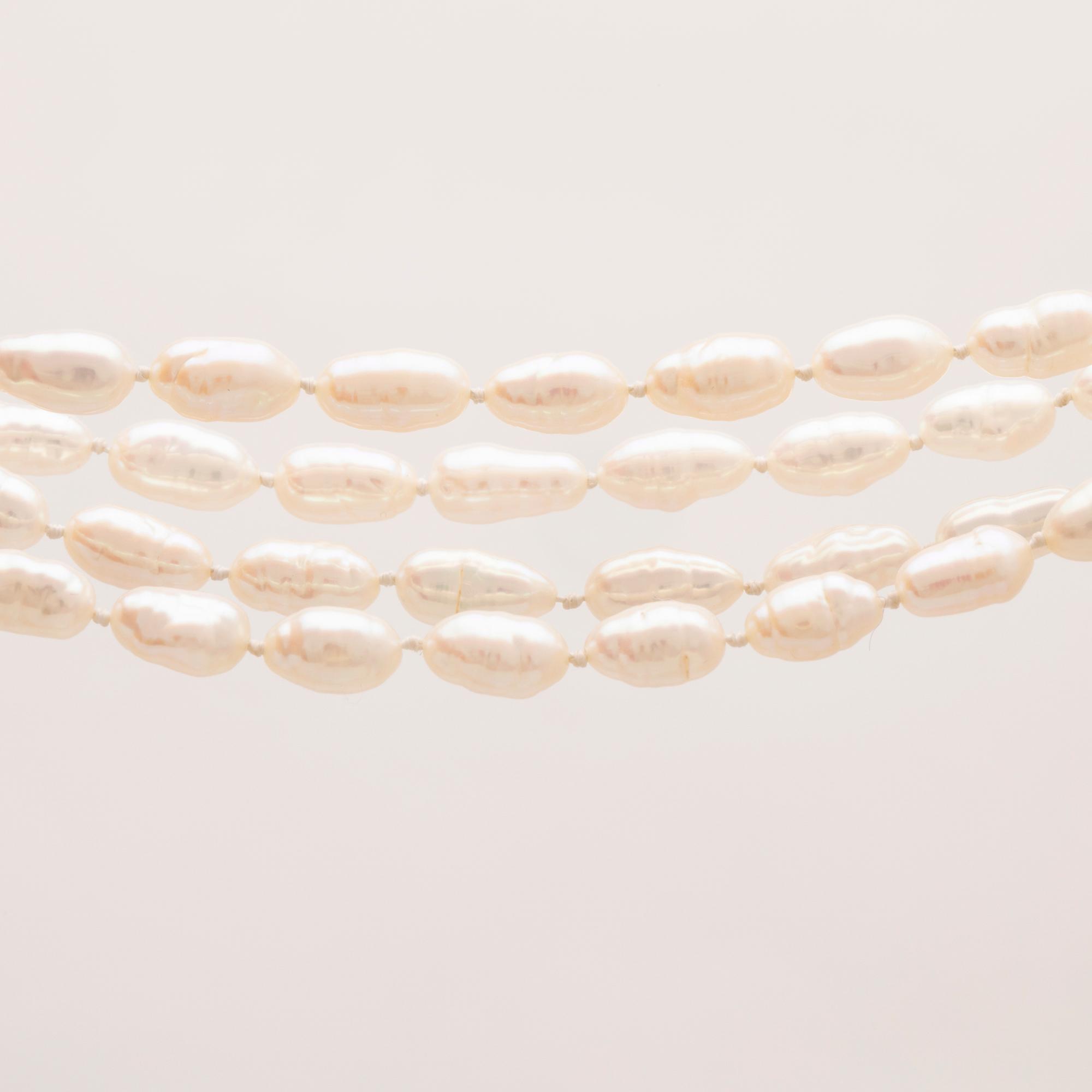 A necklace of cultured pearls set with a 14K gold lock and round brilliant cut diamonds.