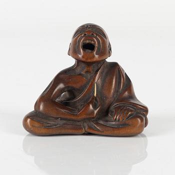 A wood netsuke of a professional sneezer, signed Gyokkō, 19th century.