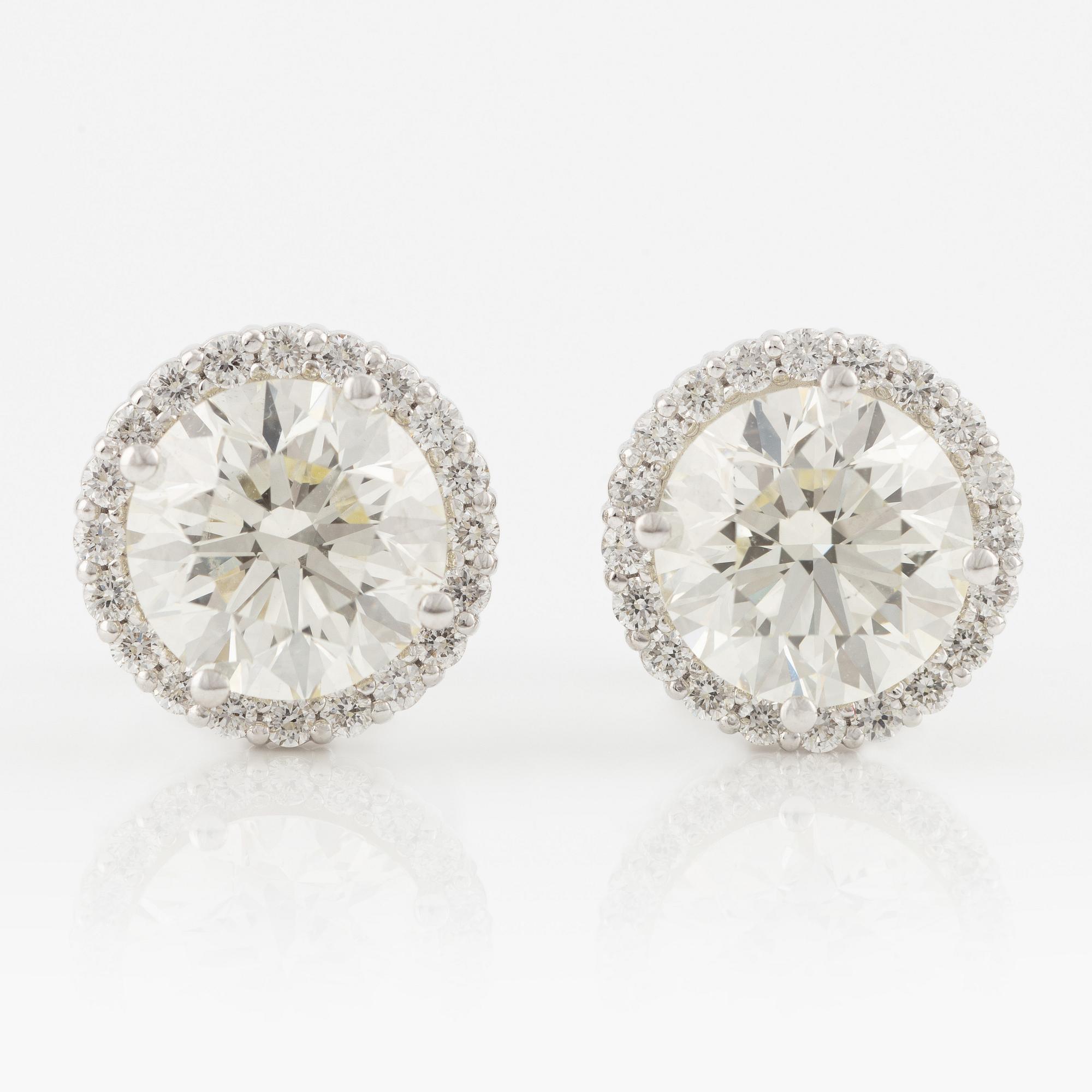 A pair of 18K gold earrings with round brilliant-cut diamonds.