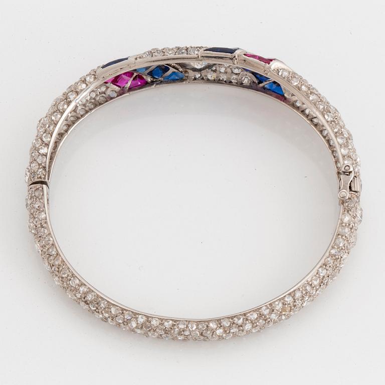 A platinum bangle set with old- and rose-cut diamonds and faceted sapphires and rubies.