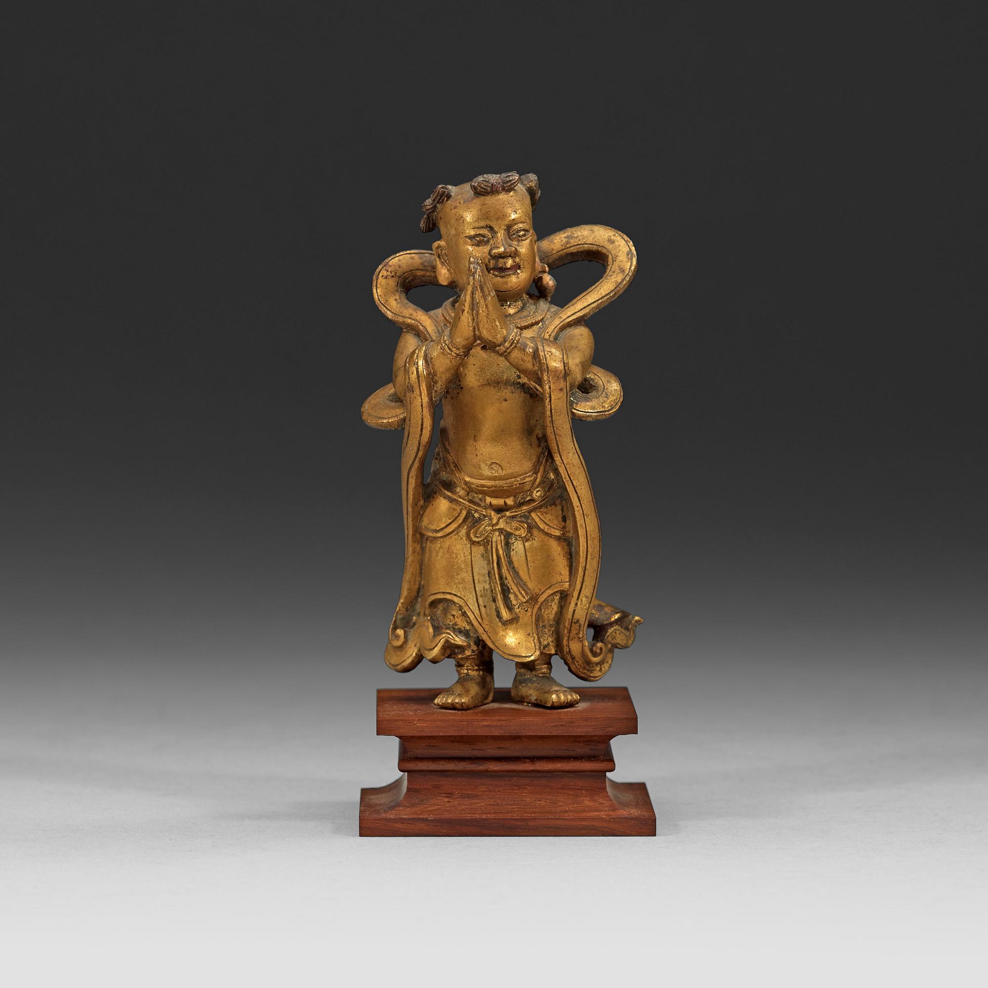 A gilt bronze figurine of a standing boy, Ming dynasty, 17th century.