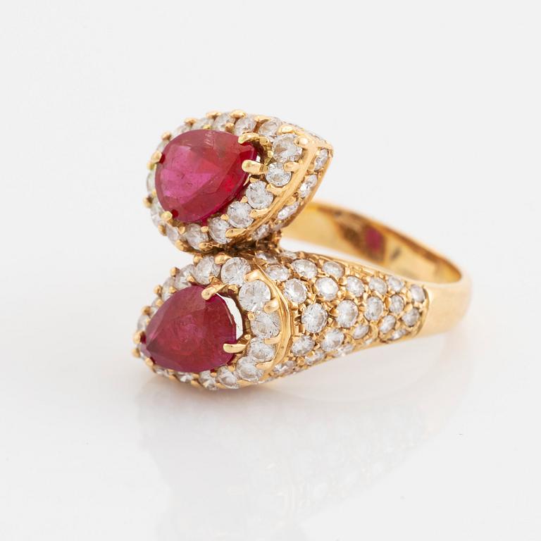 An 18K gold ring set with two facted rubies and round brilliant-cut diamonds.