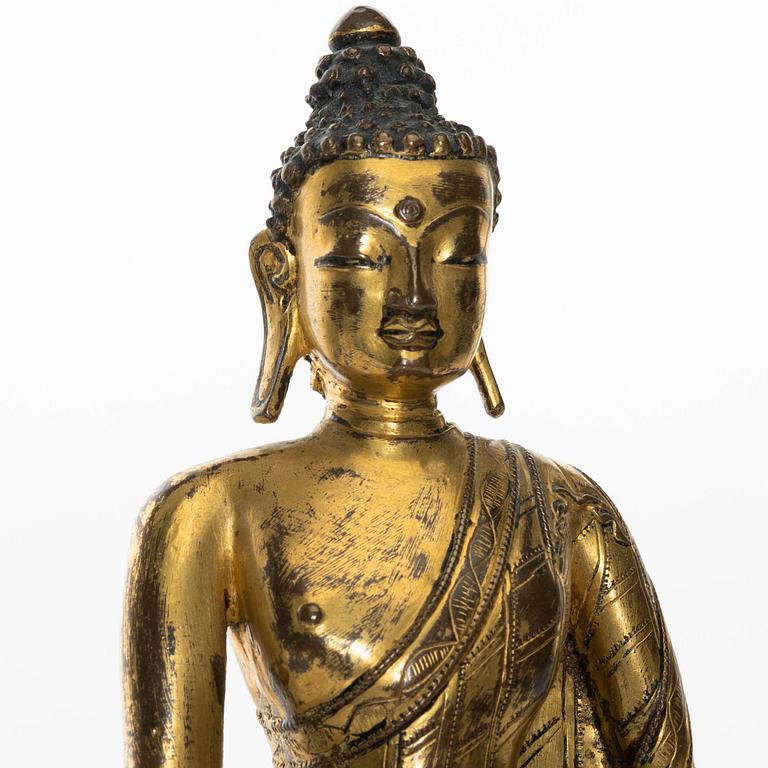 A gilt copper-alloy figure of Aksobhya Buddha, 14th/15th century, Tibet or Nepal.