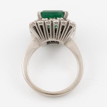 Ring in 18K white gold set with a faceted emerald and round brilliant-cut diamonds.