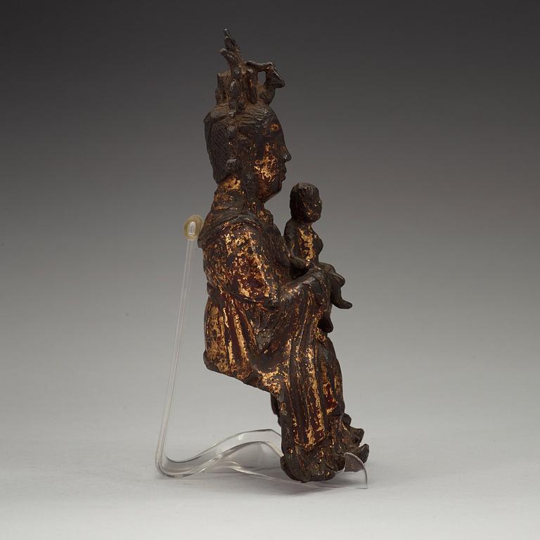 A gilt bronze figure of Guanyin holding a child, Ming dynasty (1368-1644).