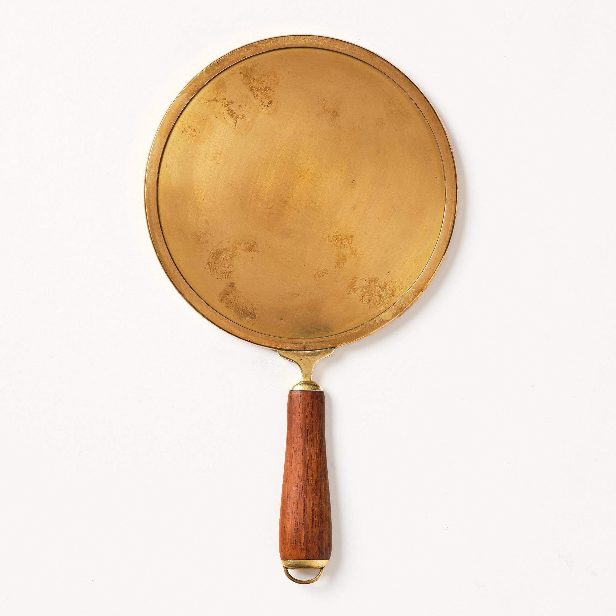 Firma Svenskt Tenn, a brass and teak hand mirror model "H 2156", mid 20th century.