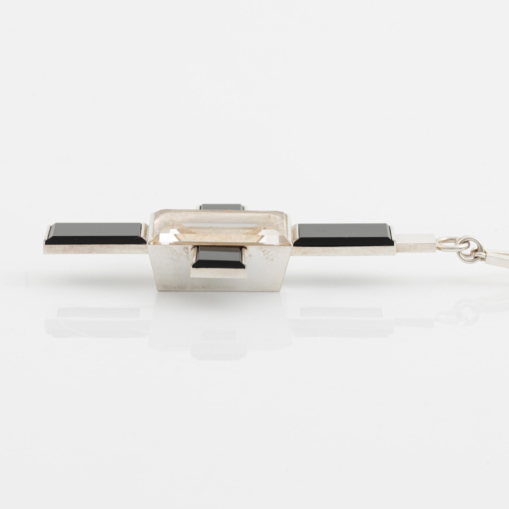 Wiwen Nilsson, hängsmycke i form av ett kors i sterlingsilver med fasettslipad bergkristall och onyx, Lund 1939.