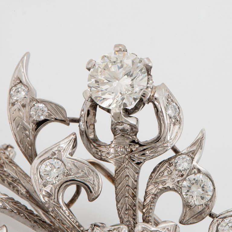 An 18K white gold brooch set with round brilliant-cut diamonds.