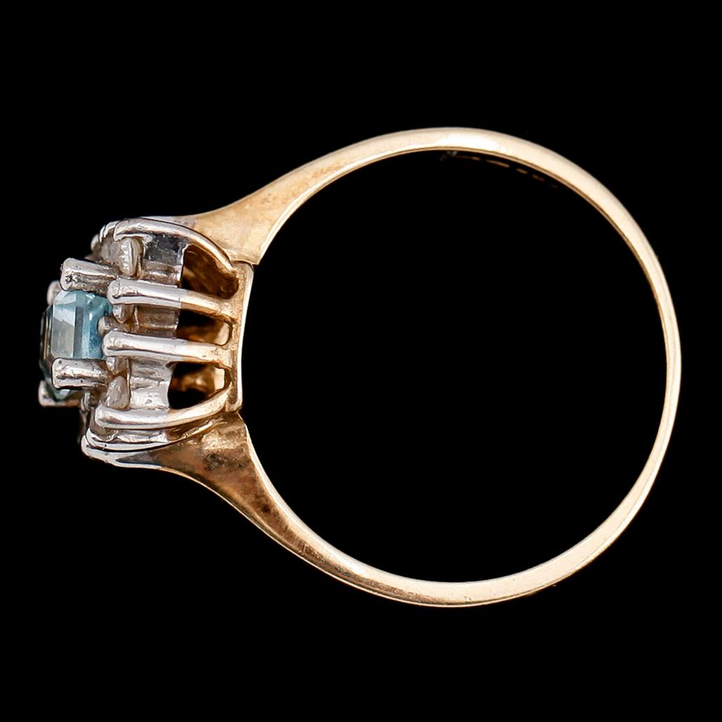 RING, 9 k guld med ljusblå fasetterad sten omgiven av vita stenar.