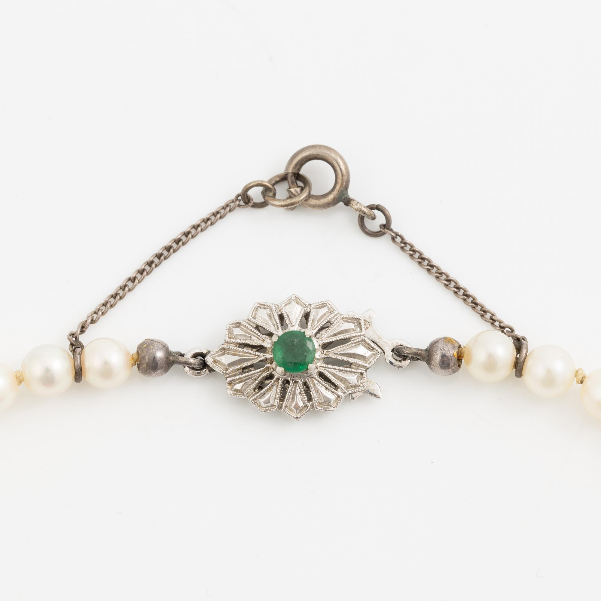 Necklace with graduated cultured pearls, with a clasp in 18K white gold set with an emerald.