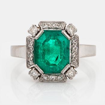 1017. An 18K white gold ring set with a faceted emerald and round brilliant-cut diamonds.