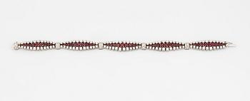 An 18K white gold bracelet set with rubies and round brilliant-cut diamonds.