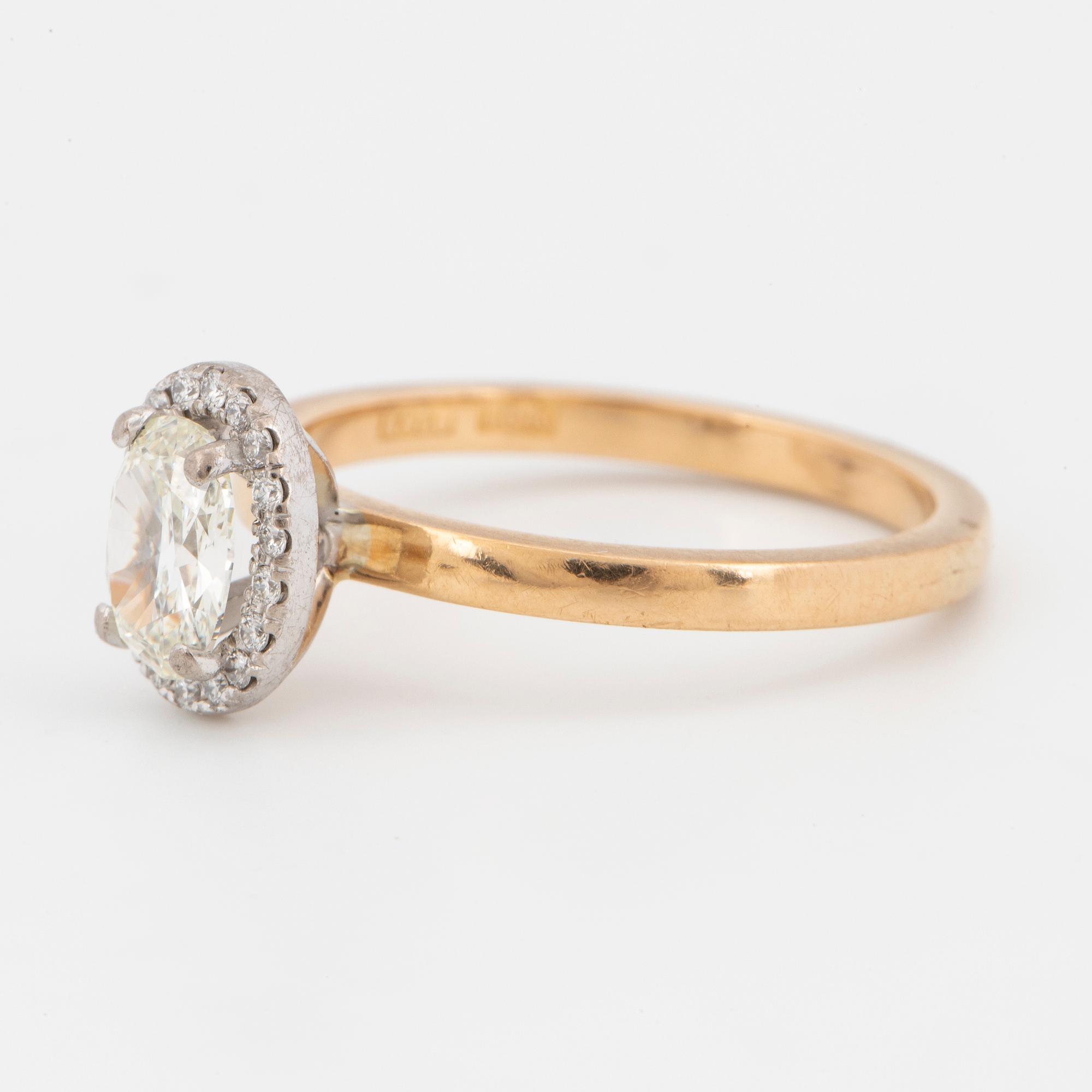 An 18k gold ring set with an oval brilliant-cut diamond.