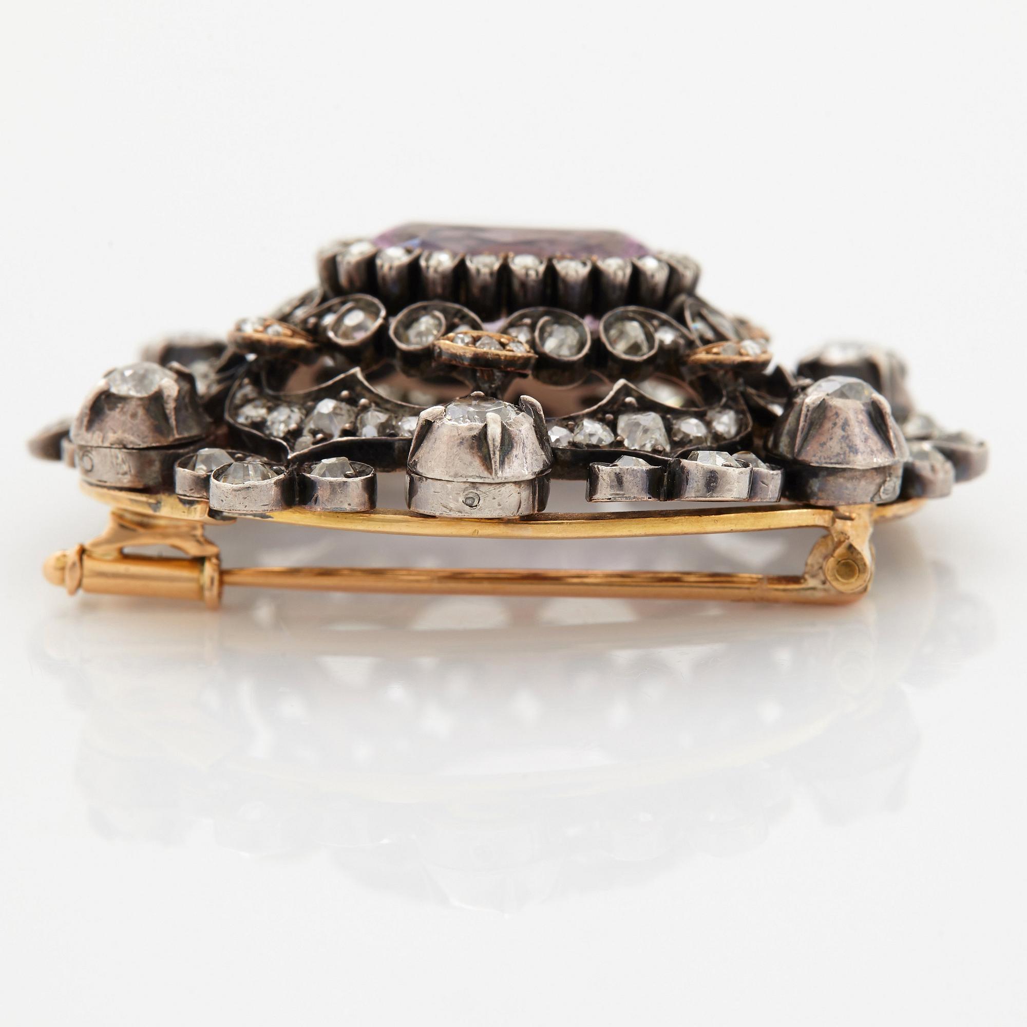 A 14K gold and silver brooch set with an oval faceted pink topaz and old- and rose-cut diamonds.