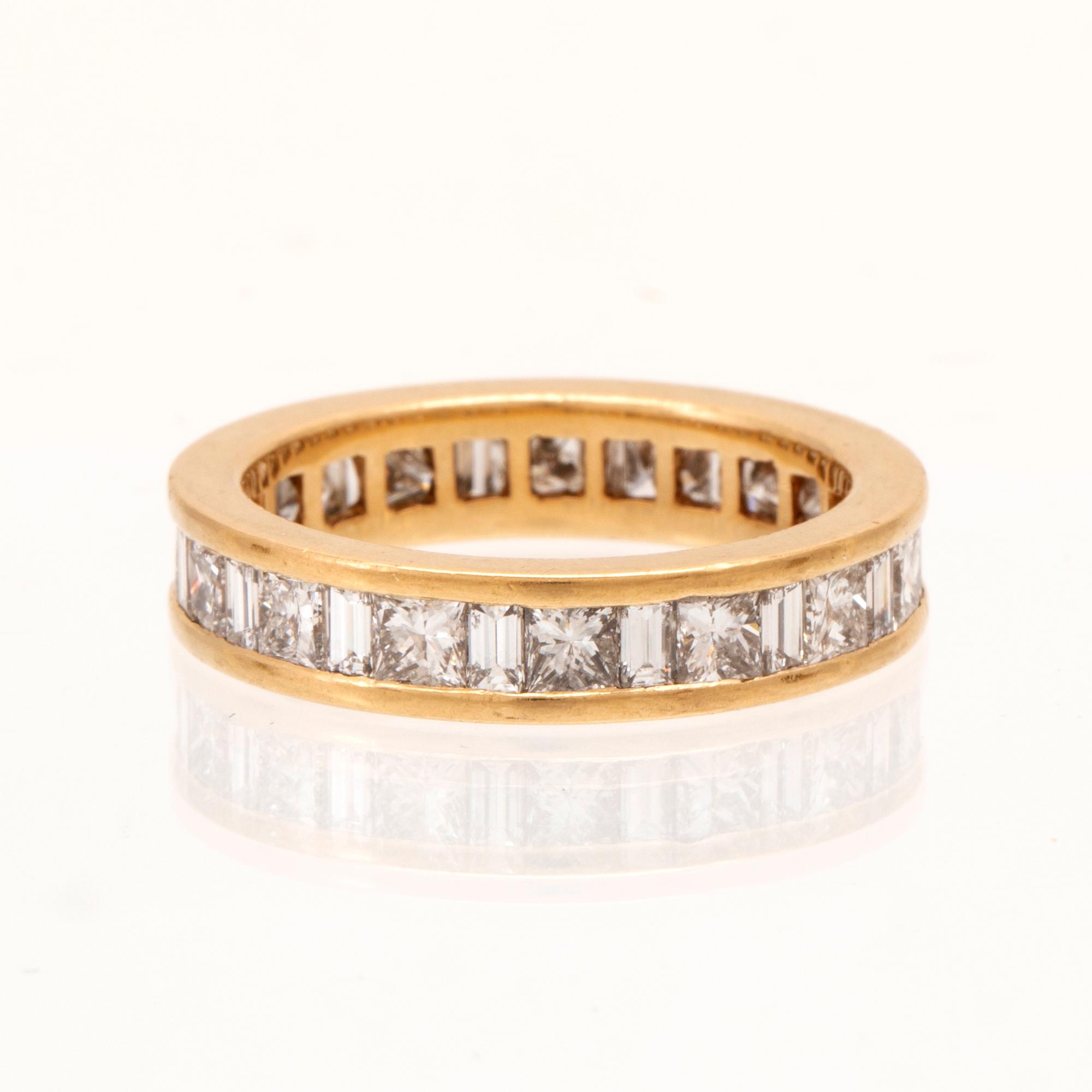 An 18K gold eternity ring set with baguette and princess cut diamonds by Hartmann's Denmark.